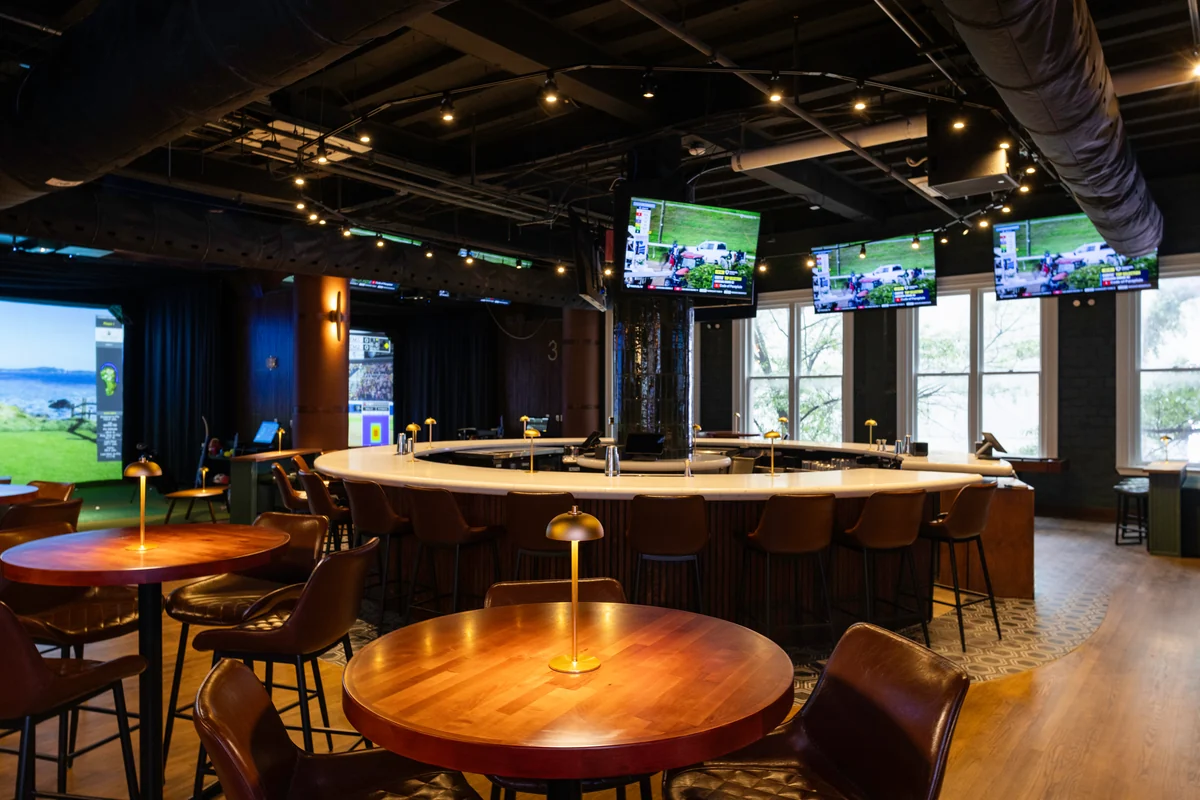 PSC central bar, green seats, brass table lights, tall windows and sports screens