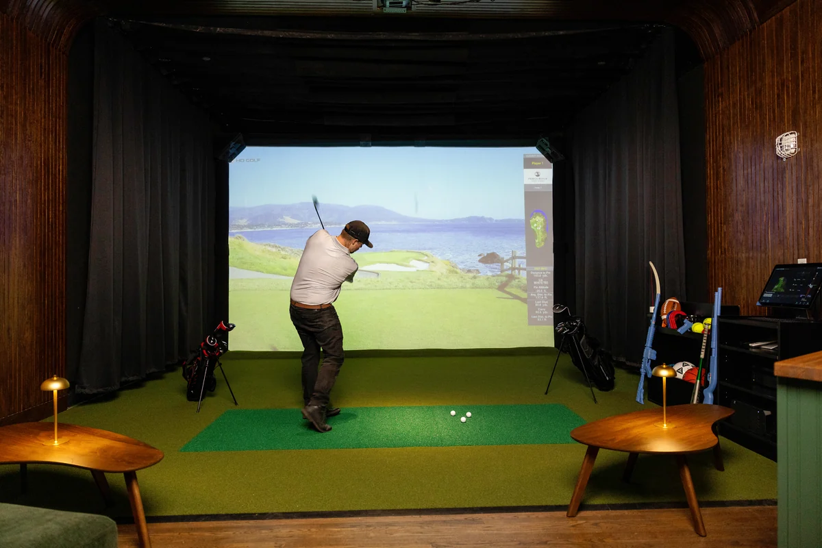 A guest takes a golf swing in a PSC sports suite