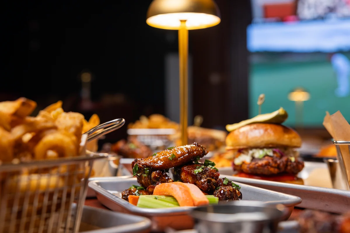 Wings, sandwiches and sides on a PSC table beneath brass lights